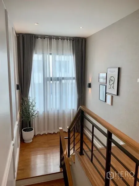 独立式住宅 出售 - 楼梯平台，木地板与金属栏杆，大窗帘与墙面装饰画。