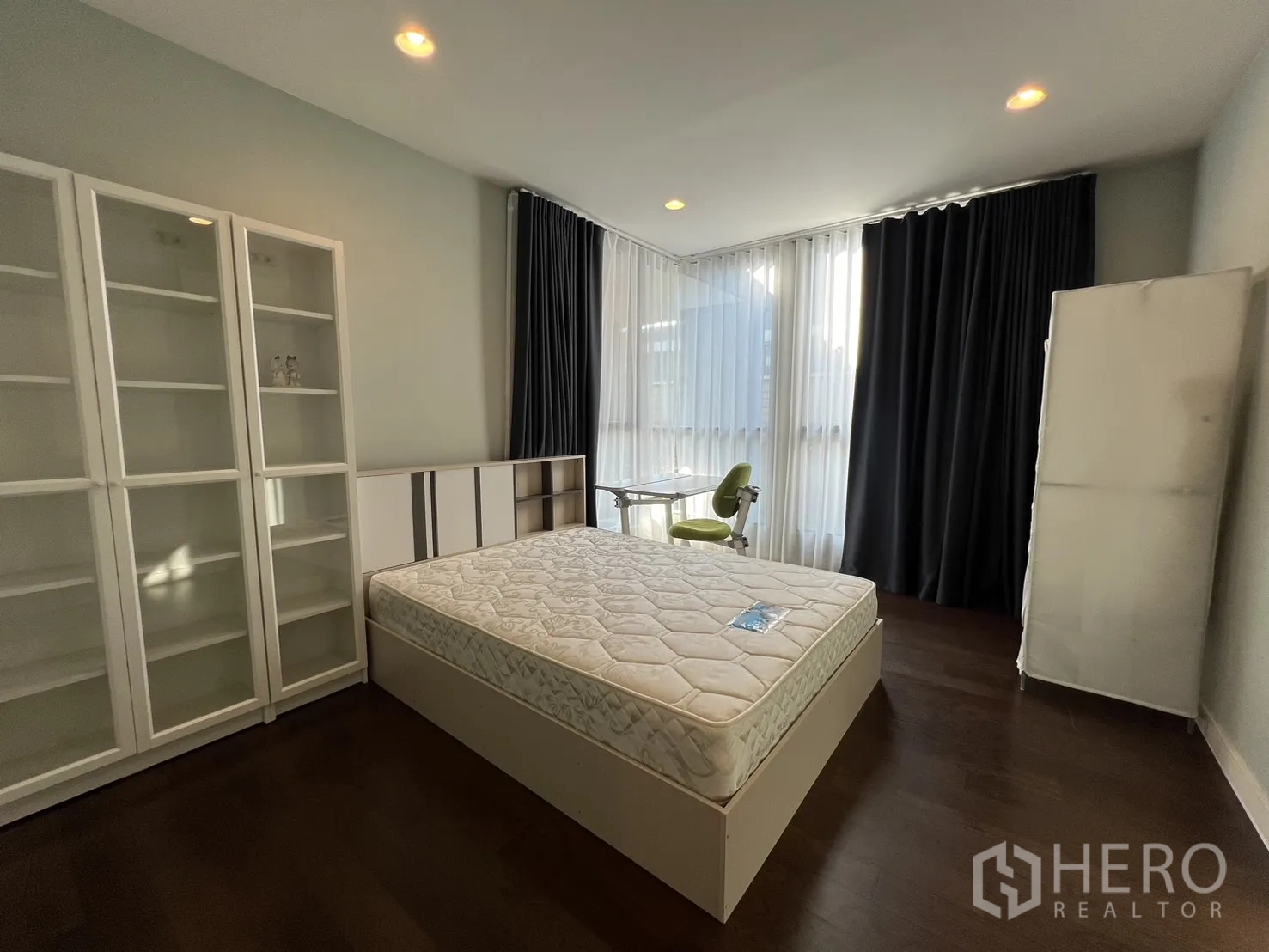 Detached House for rent or sale in Bang Kapi, Bangkok - Corner bedroom with wraparound windows, shelving units and study desk.