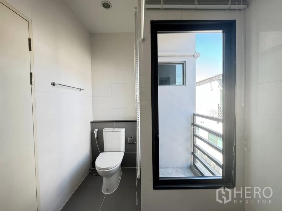 Townhouse for rent in Saphan Sung, Bangkok - Bright bathroom with a window, toilet and towel rail.