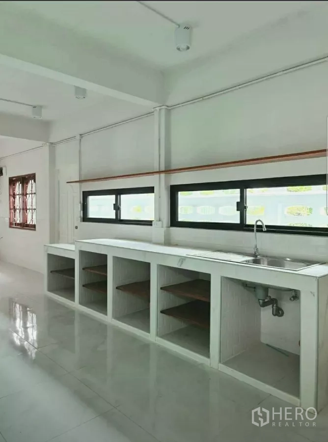 Home Office for rent in Lat Phrao, Bangkok - Built‑in counter with stainless sink and open shelving under horizontal windows.