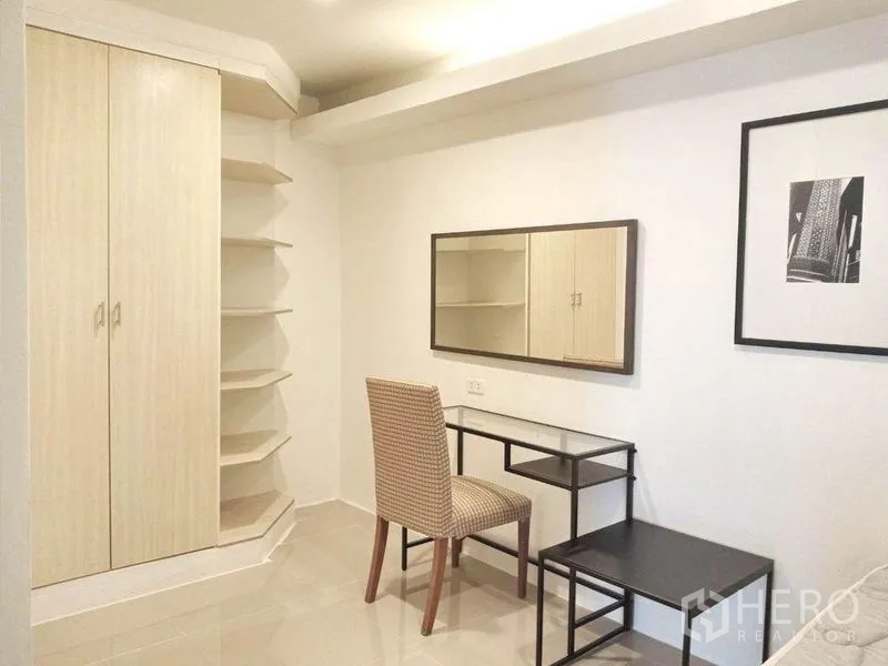 Condominium for rent in Khlong Toei, Bangkok - Corner wardrobe with open shelving and study desk with mirror in the second bedroom.