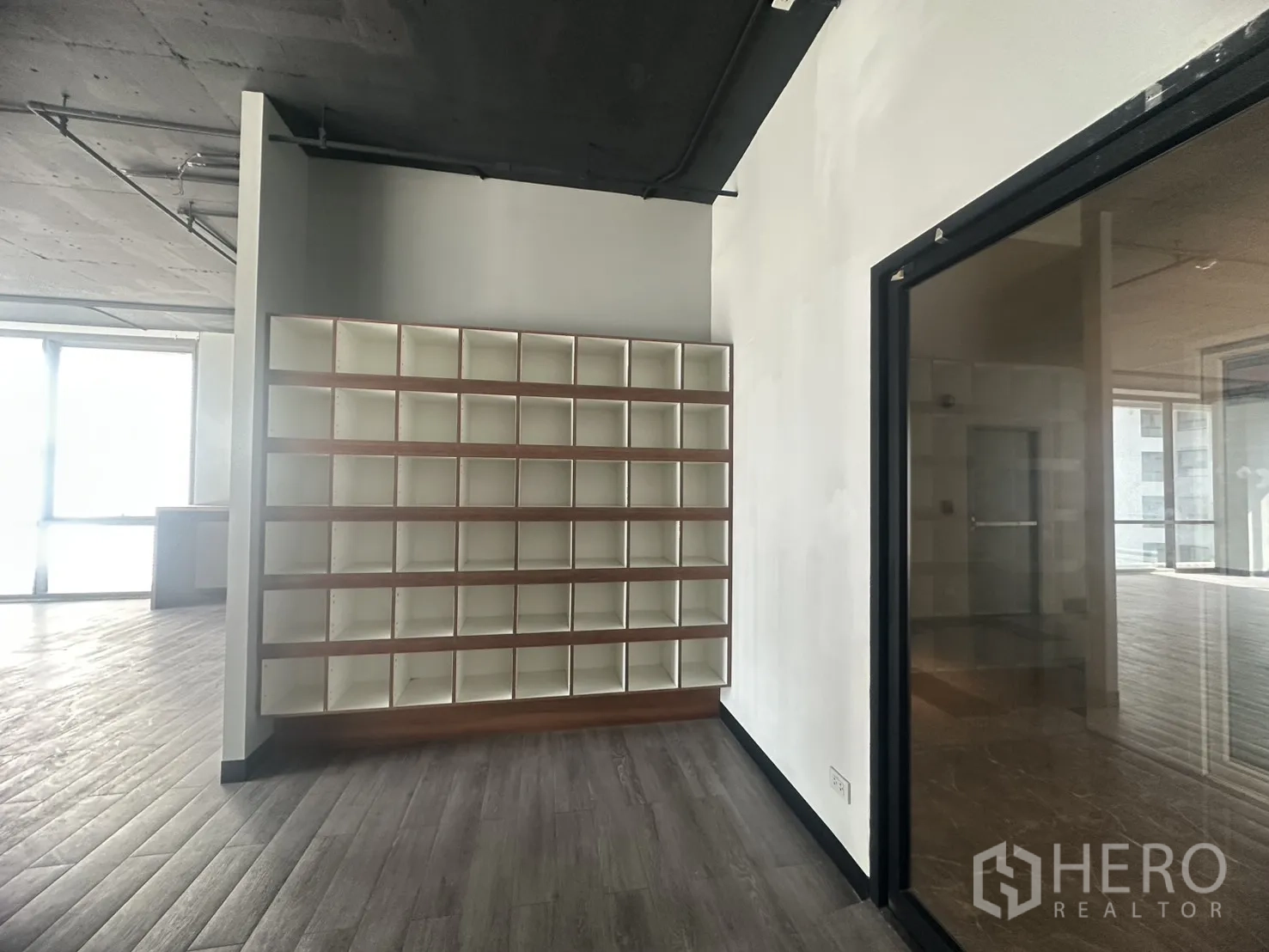 Office Space for rent in Khlong Toei, Bangkok - Wall of cubby storage shelves next to a glass door inside the office.