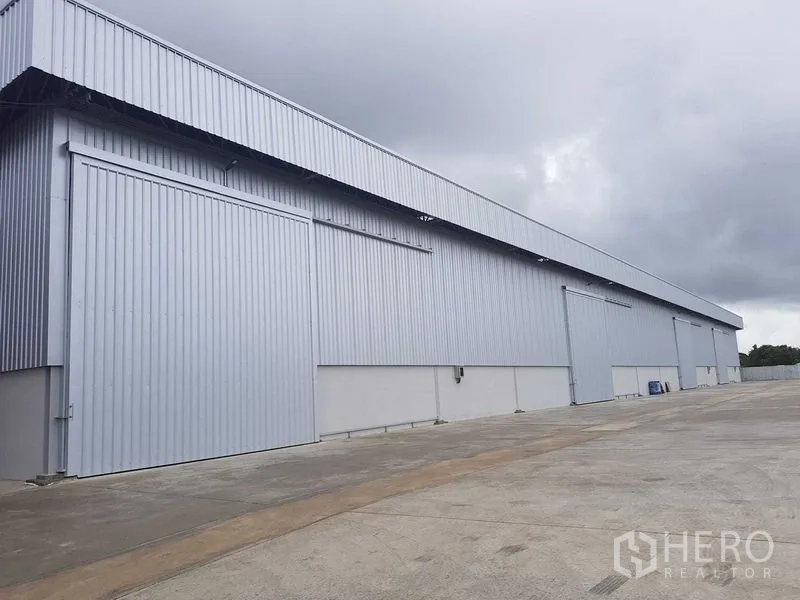 Warehouse for rent in Lat Krabang, Bangkok - Exterior of metal-clad warehouse with wide sliding doors and an ample concrete yard.