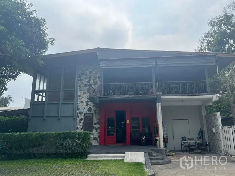 Detached House for rent in Khlong Toei, Bangkok - Close-up of the house showing stone facade, covered balcony terrace and bold red entrance.