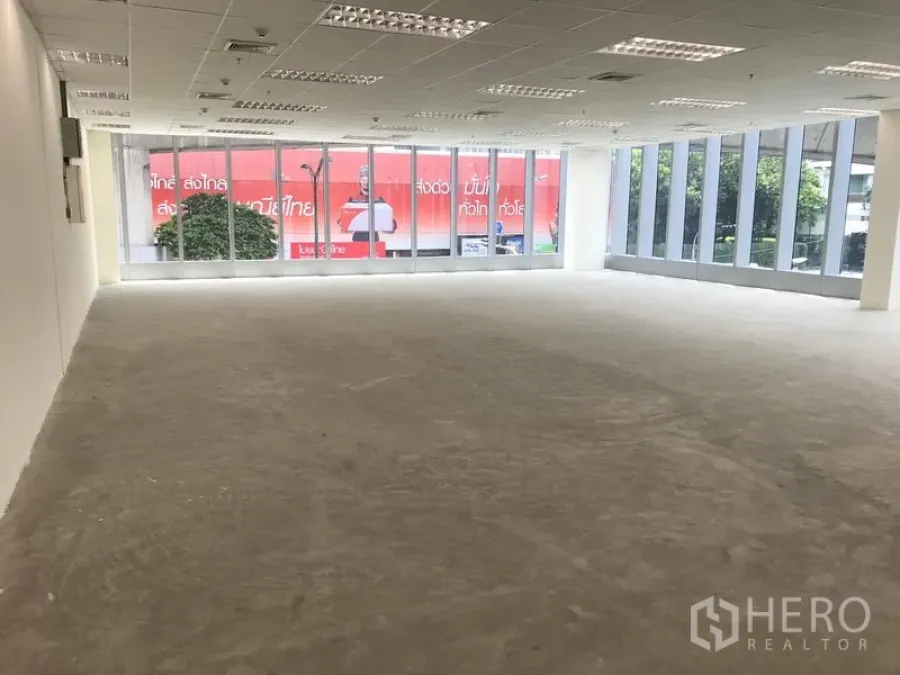 办公空间 出租在Khlong Toei, Bangkok - 开放式办公室，双面落地窗、网格吊顶照明与未铺装的混凝土地面。