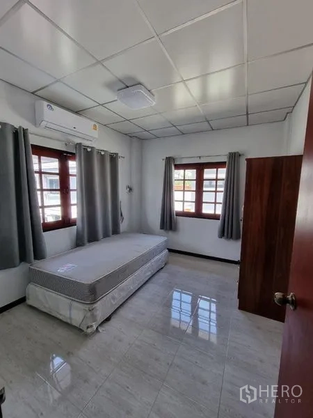 Detached House for rent in Nonthaburi - Bright single bedroom with air conditioning, corner windows, and curtains.