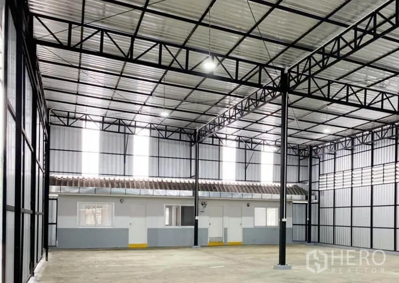 Warehouse for rent in Din Daeng, Bangkok - High-clearance warehouse interior with steel trusses, LED lighting, concrete floor, and built-in office rooms.
