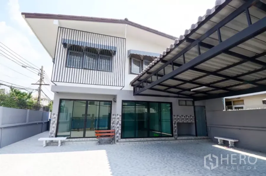 Home Office for rent in Lat Phrao, Bangkok - Two‑storey corner home office with covered carport, sliding glass doors and paved forecourt.