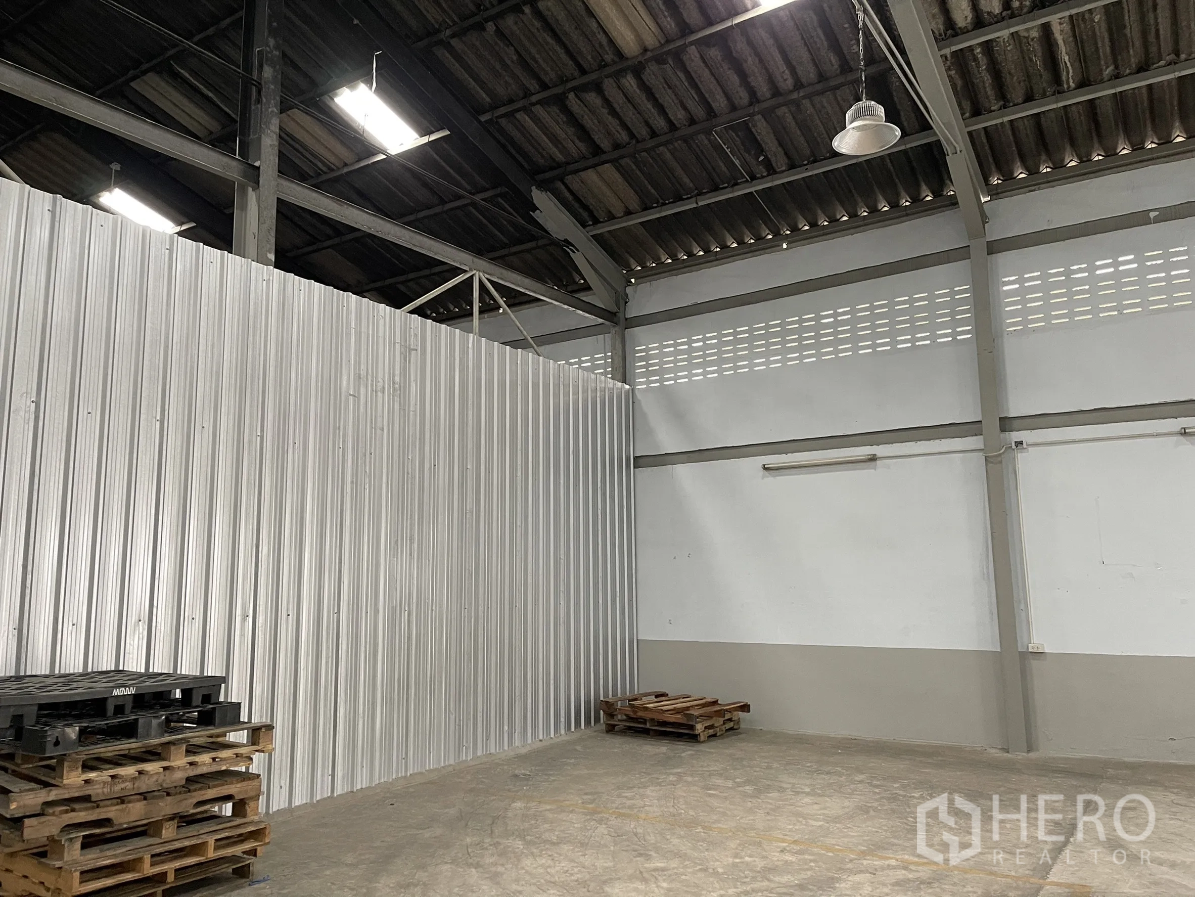 Factory for rent in Mueang Samut Prakan, Samut Prakan - Corner of the factory with metal sheet partition and wooden pallets.