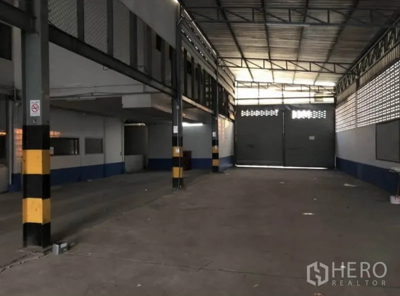 คลังสินค้า ให้เช่าในBang Phli, Samut Prakan - อาคารโหลดสินค้าภายในโล่ง ประตูบานคู่กว้าง และเสาเตือนความปลอดภัยสีเหลืองดำ