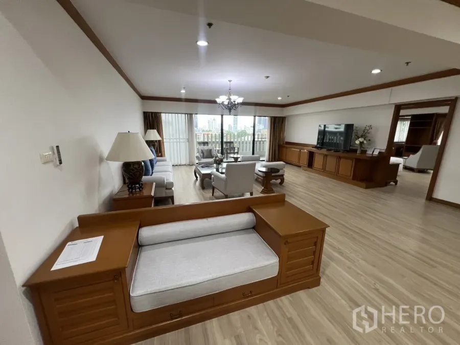 Condominium for rent in Khlong Toei, Bangkok - Large living room with sofa set, TV console, chandelier and balcony with city view.