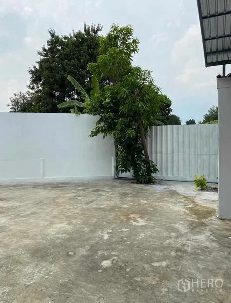 货栈 出租在Bang Khen, Bangkok - 院子转角，水泥地面与靠墙的大树