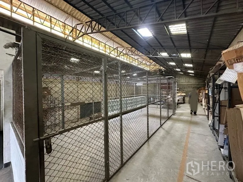 Factory for rent in Lam Luk Ka, Pathum Thani - Mezzanine walkway with caged storage and shelving under skylight.