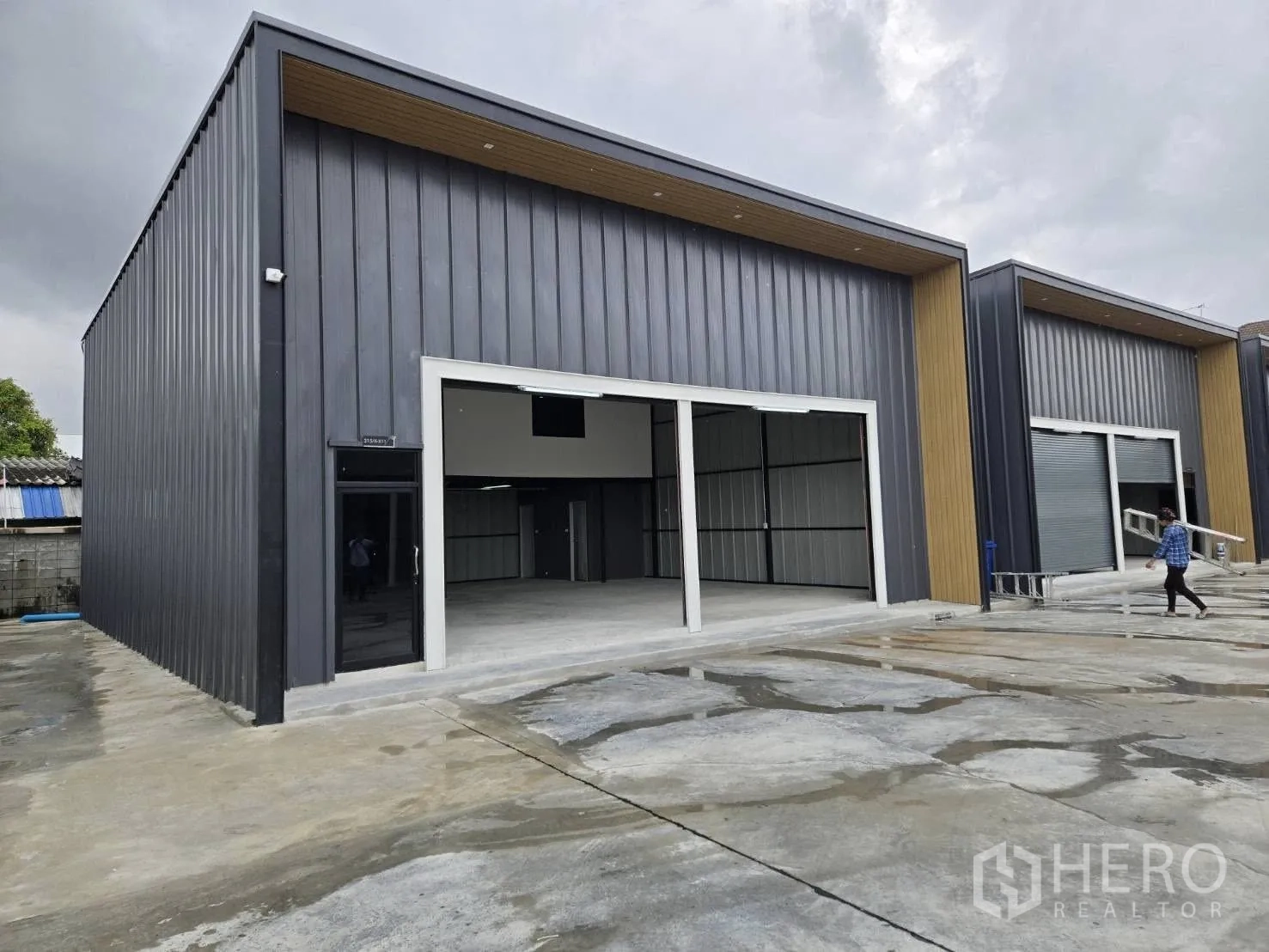 Warehouse for rent - Row of new warehouses with large bay doors and a side glass entry, set along a wide concrete driveway.