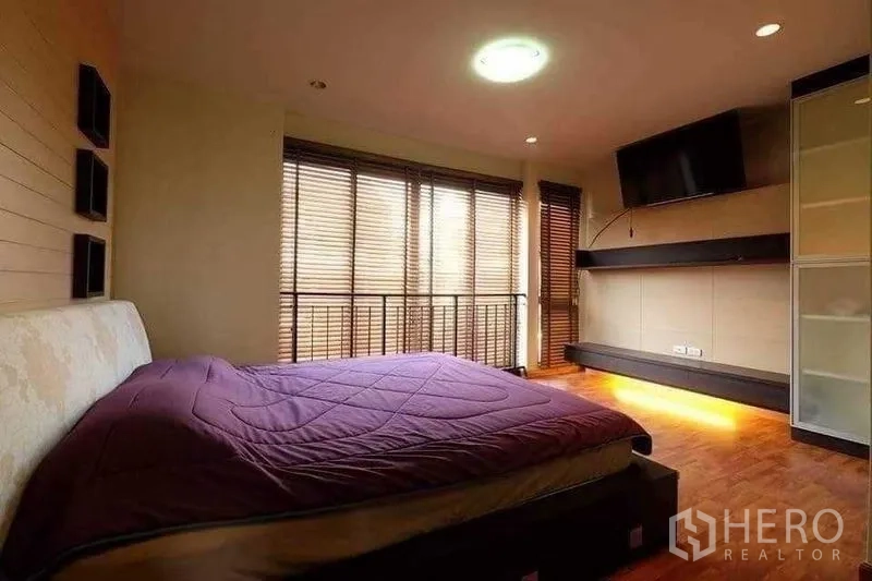 Townhouse for rent in Phra Khanong, Bangkok - Master bedroom with TV wall, ambient lighting and floor-to-ceiling blinds.