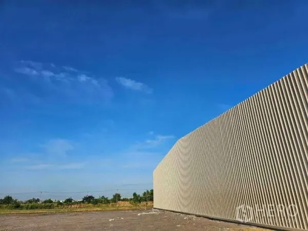 Warehouse for rent in Pak Kret, Nonthaburi - Exterior corrugated metal facade of the warehouse against a bright blue sky.