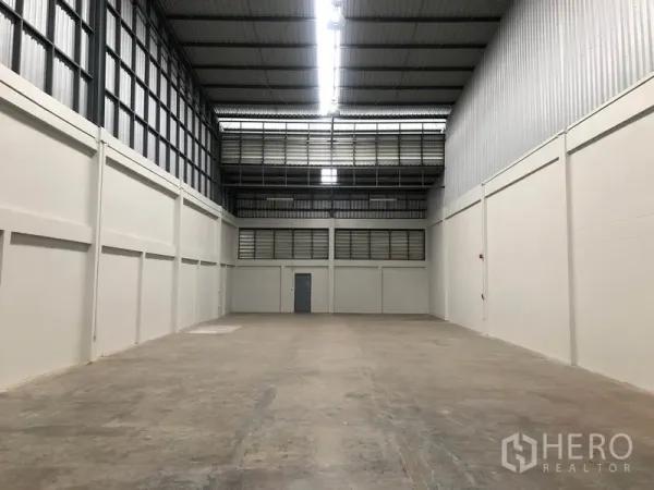 Factory for rent in Pak Kret, Nonthaburi - Spacious high-bay warehouse with concrete floor, steel roof and rear service door.