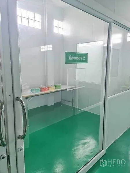 Factory for sale in Bang Pa-in, Phra Nakhon Si Ayutthaya - Glass room labeled packing room 2 with a long worktable and containers.