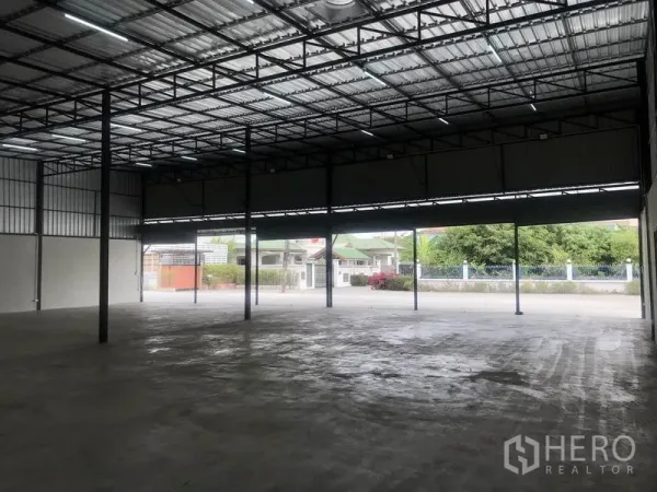 Warehouse for rent in Pathum Thani - Open-span warehouse with large entrance, ample driveway, and view of the surrounding neighborhood in Pathum Thani.