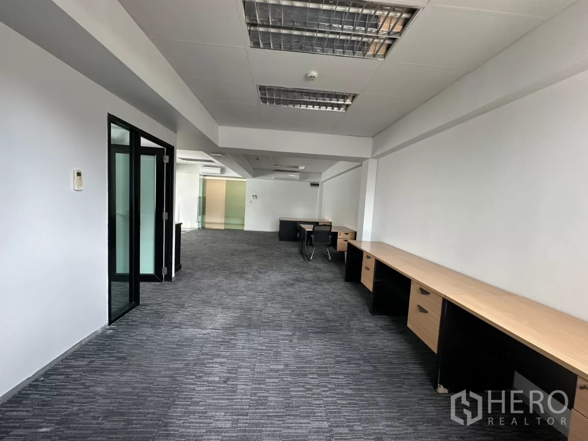 Office Space for rent in Watthana, Bangkok - Wide office corridor with glass-partitioned room, rows of built-in desks and ceiling lighting.