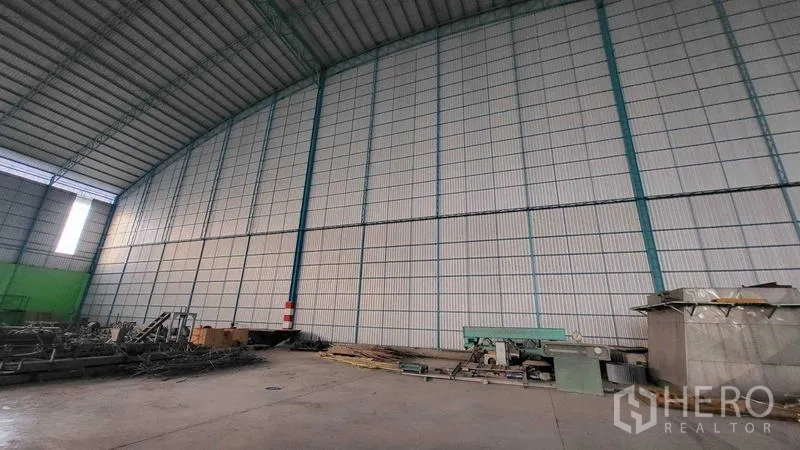 Factory for rent in Sai Noi, Nonthaburi - Interior view showing high corrugated steel wall and roof with industrial equipment.