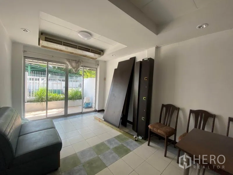 Townhouse for rent in Watthana, Bangkok - Ground-floor living area with sliding glass doors to the front patio and cassette AC.