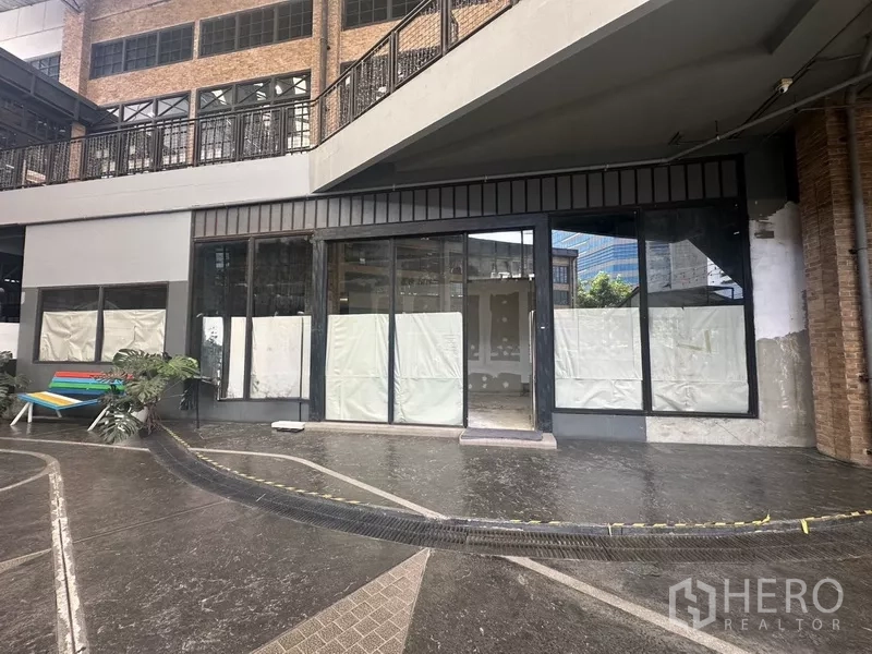Retail Space for rent in Khlong Toei, Bangkok - Ground-floor retail unit in Khlong Toei with large glass storefront under a covered walkway.