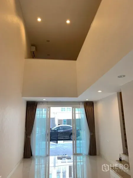 Townhouse for rent in Bang Na, Bangkok - Open living area with recessed lights and sliding doors to the front patio and carport