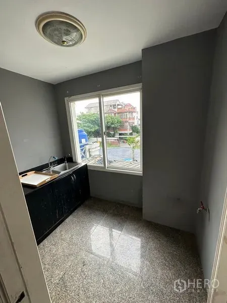 Townhouse for rent in Bang Kapi, Bangkok - Compact kitchen with window, black countertop, stainless sink and neighborhood view.