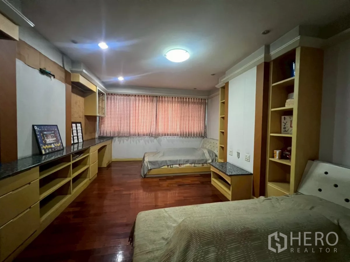 Shophouse for rent in Bang Rak, Bangkok - Spacious bedroom with twin beds, built-in shelves and wood floors.