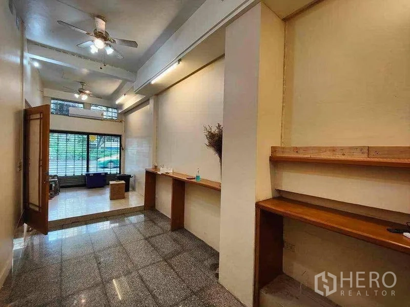 Retail Space for rent in Khlong Toei, Bangkok - Open-plan shop area with ceiling fans and wooden display shelves looking toward the glass storefront.