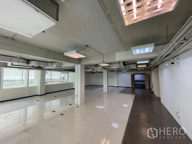 Office Space for rent in Ratchathewi, Bangkok - Open-plan office interior showing exposed ductwork, grid lighting and reflective floor tiles.