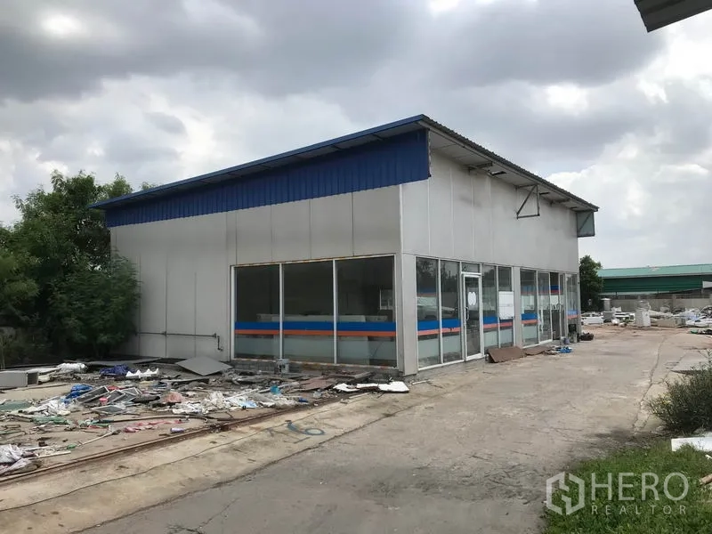 Warehouse for rent in Khlong Sam Wa, Bangkok - Separate glass-fronted outbuilding suitable for a showroom or workshop next to a paved yard.