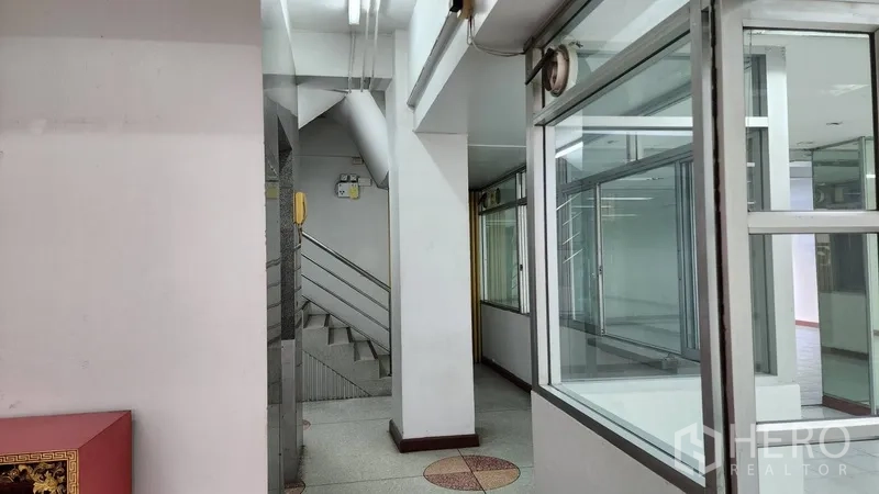 Office Space for rent or sale in Khlong Toei, Bangkok - Interior corridor showing a stairway and aluminum-framed windows.