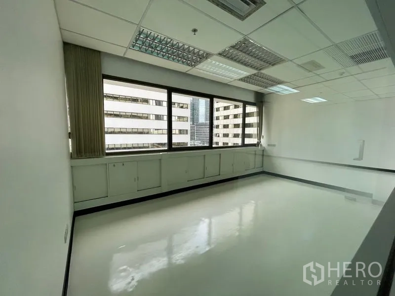 Office Space for rent in Bang Rak, Bangkok - Private office with built-in cabinets under windows and views of nearby towers.