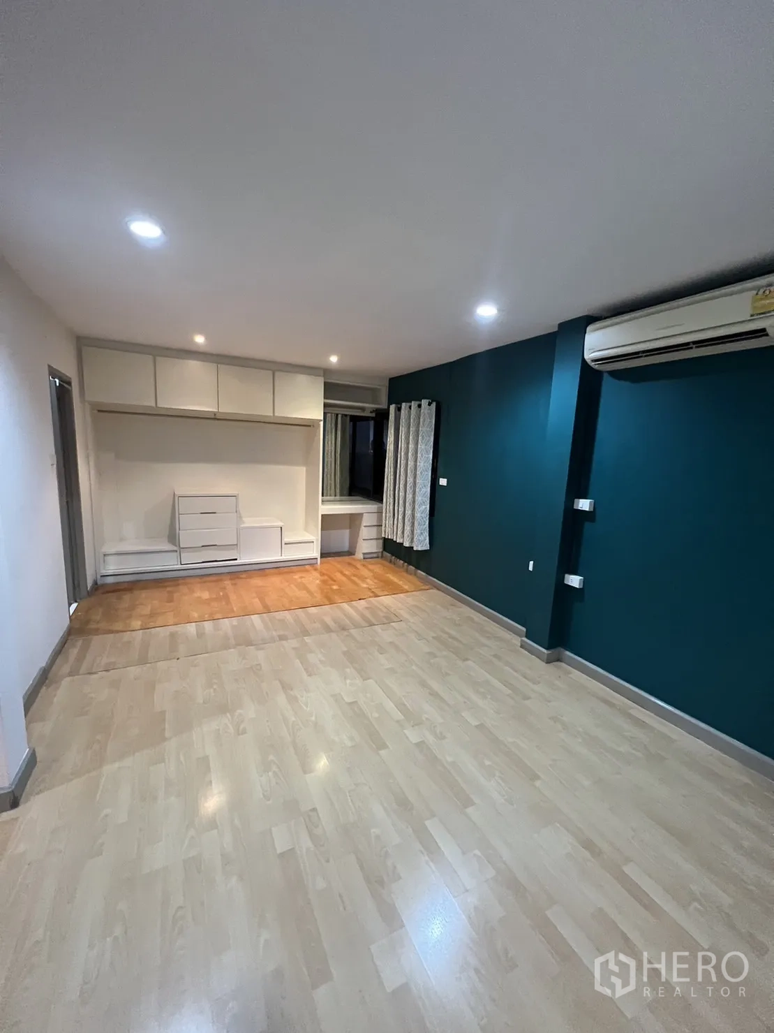 Townhouse for rent in Watthana, Bangkok - Master bedroom wide angle showing built-ins and a teal feature wall.