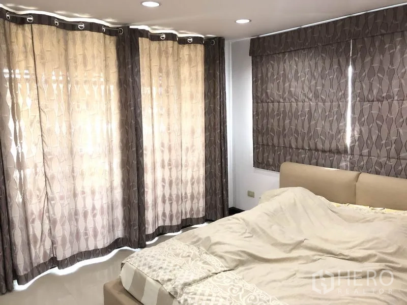 Home Office for rent in Wang Thonglang, Bangkok - Corner bedroom with patterned curtains, recessed lighting and upholstered bed.