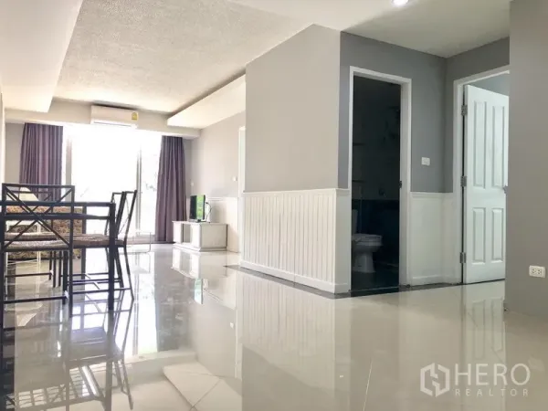 Condominium for rent in Khlong Toei, Bangkok - Dining space and hallway with glossy floors leading to bedrooms in the condo.
