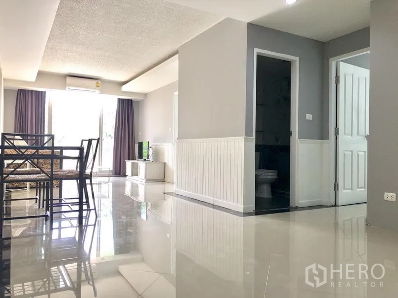 Condominium for rent in Khlong Toei, Bangkok - Dining space and hallway with glossy floors leading to bedrooms in the condo.