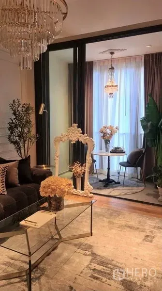 Condominium for rent in Khlong Toei, Bangkok - Living area opening to a glass‑enclosed nook with a bistro table, pendant light and decor accents.