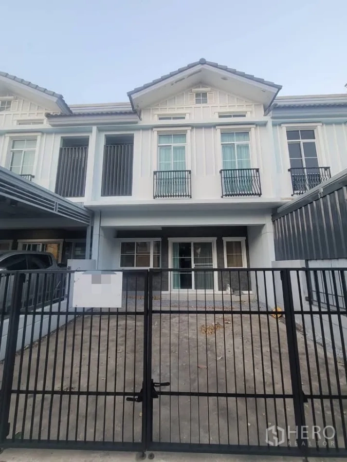 Townhouse for rent in Prawet, Bangkok - Contemporary townhouse facade with gated driveway and small balconies.