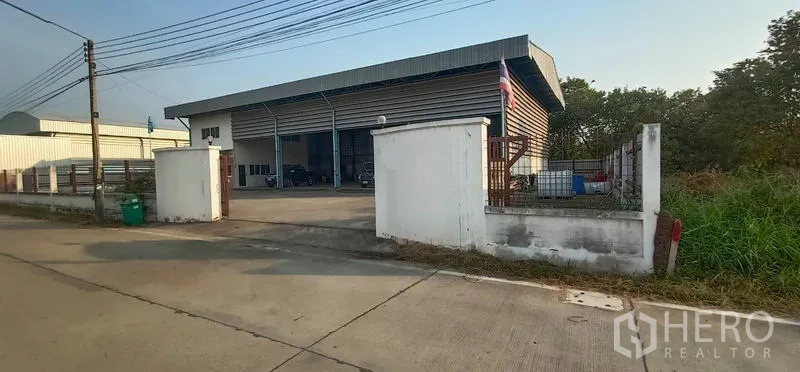 Warehouse for rent in Khlong Luang, Pathum Thani - Front elevation of the warehouse compound with a low boundary wall and roadside access.