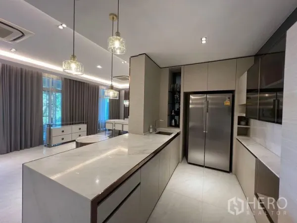 Detached House for sale - Contemporary Western kitchen with long marble island, pendant lights and double-door fridge facing the living area.