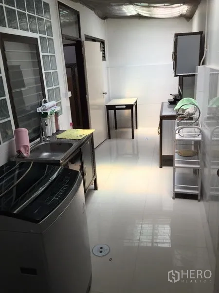 Townhouse for rent in Phra Khanong, Bangkok - Bright galley kitchen with sink, washing machine and glass-block window.