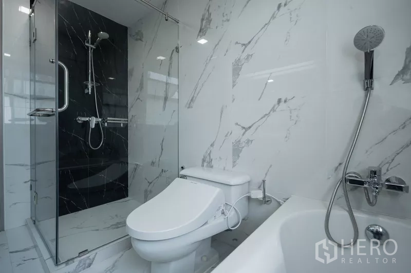 Apartment for rent - Bathroom with marble-effect tiles, glass shower, bathtub and handheld shower.