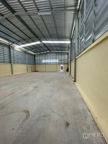 Warehouse for rent in Lam Luk Ka, Pathum Thani - Side view of ventilated metal-clad warehouse interior with smooth concrete slab.