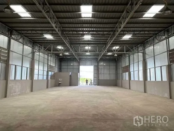 Warehouse for rent in Mueang Pathum Thani, Pathum Thani - Spacious high-ceiling warehouse interior with steel trusses, skylights and concrete floor.