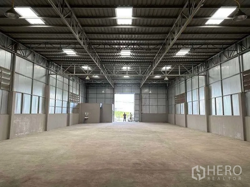 Warehouse for rent in Mueang Pathum Thani, Pathum Thani - Spacious high-ceiling warehouse interior with steel trusses, skylights and concrete floor.