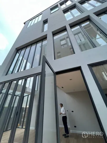 Home Office for sale in Wang Thonglang, Bangkok - Contemporary multi-storey home office facade in Wang Thonglang, Bangkok with floor-to-ceiling windows and a tall pivot door.