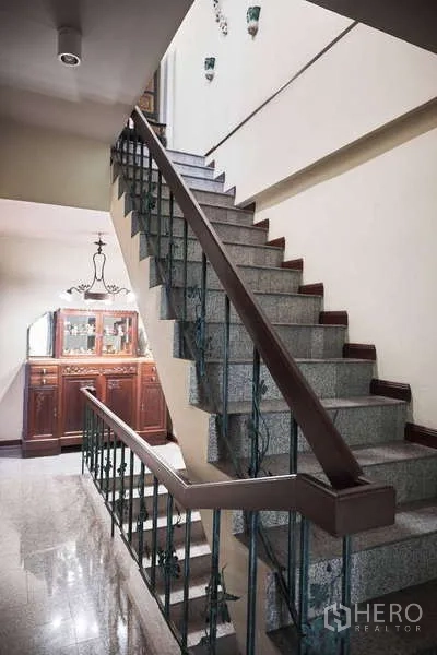 Townhouse for rent in Khlong Toei, Bangkok - Wide internal staircase with metal balustrade and cabinet at landing